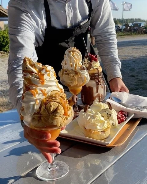 Servitör räcker fram en bricka med flera glasskreationer på Källa Glassgård